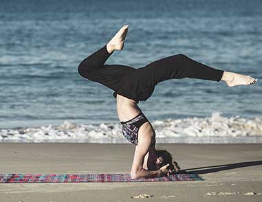 Девушка занимается йогой на берегу моря на коврике