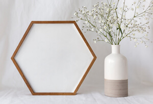 На столе шестигранная рамка рядом ваза с цветочками